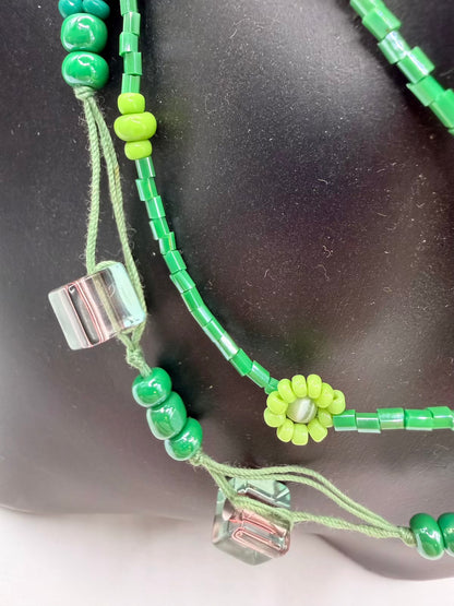 Green beaded necklace with a silver clasp on a dark background