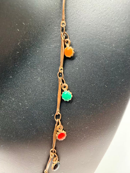 Gold necklace with colored gemstones on a dark surface