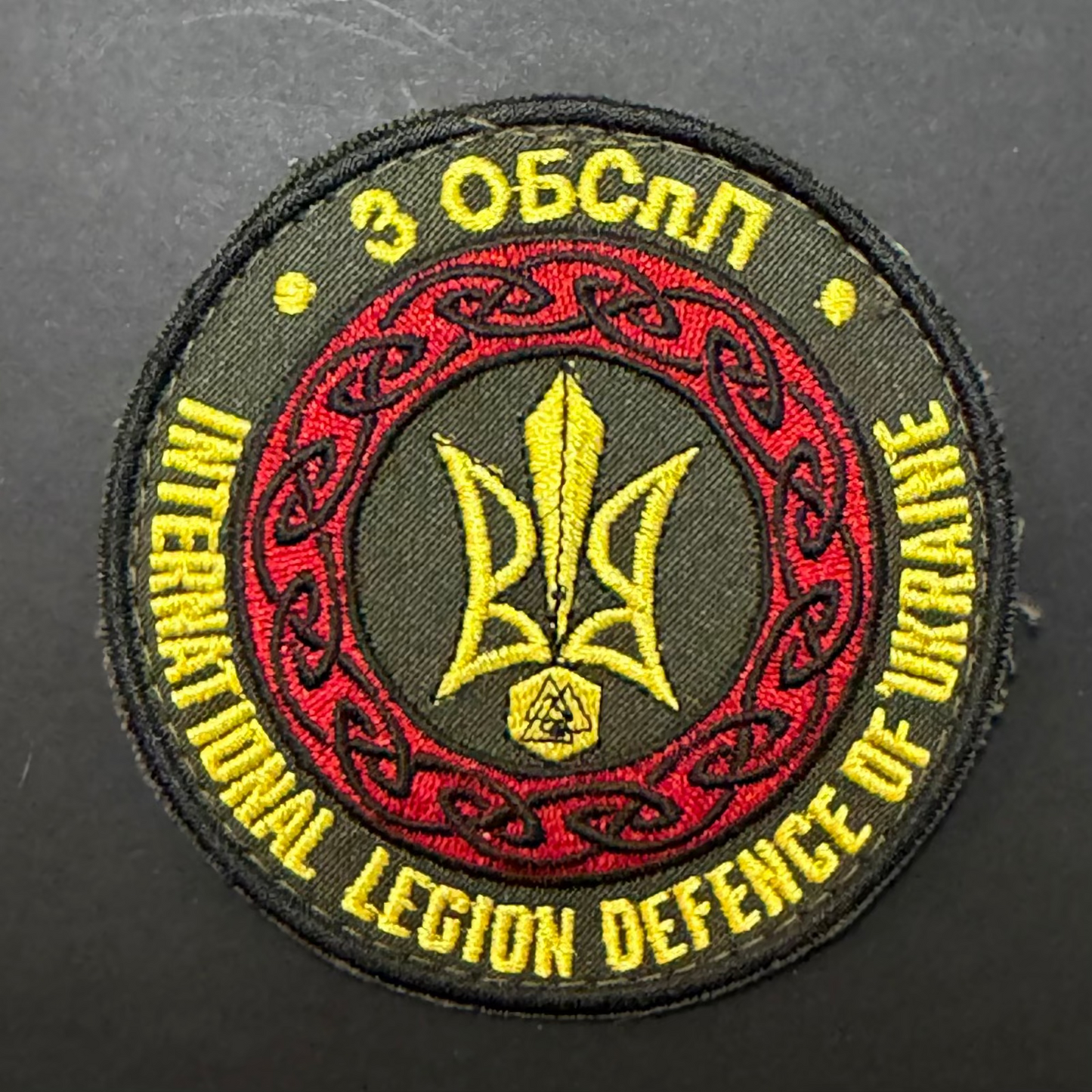Embroidered patch with text and emblem on a dark background