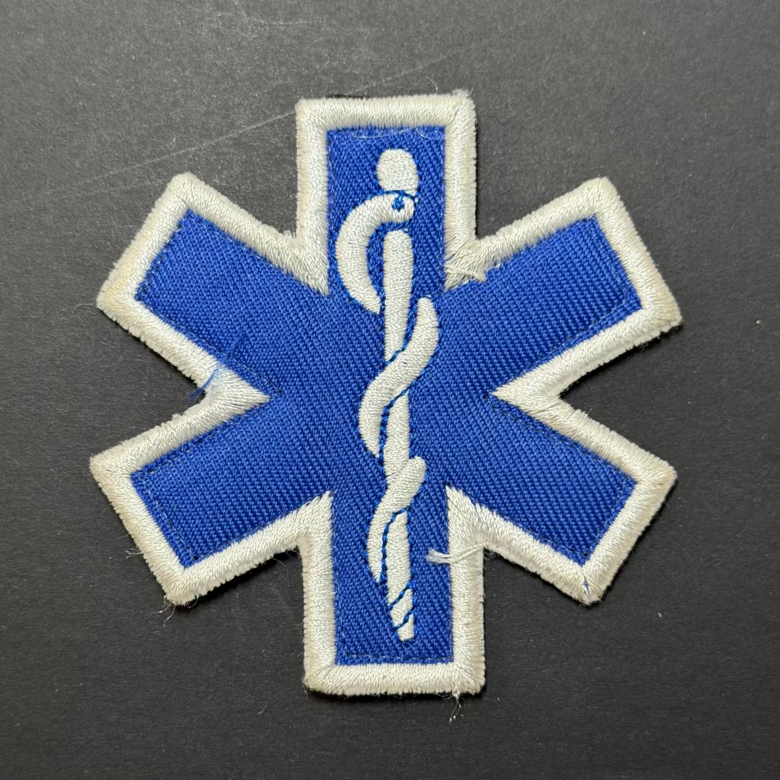 Blue and white medical symbol patch on a dark background