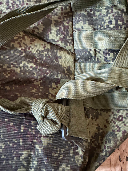 Close-up of a camouflage bag with straps on a wooden surface