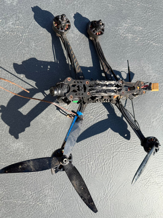 Drone lying on a textured surface with visible propellers