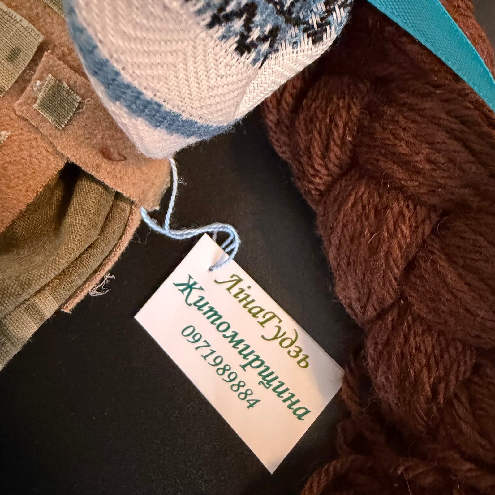 Textile items including yarn and fabric with a name tag on a dark surface