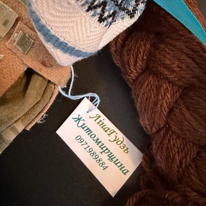 Textile items including yarn and fabric with a name tag on a dark surface