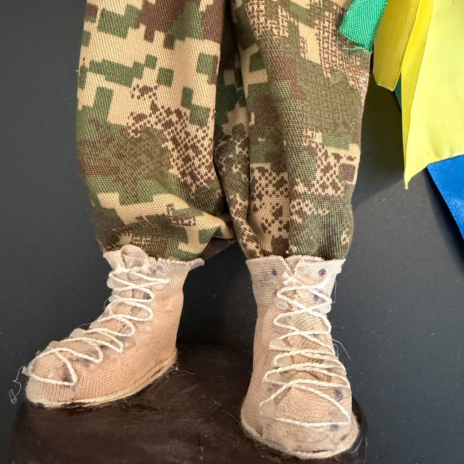 Camouflage pants and beige boots on a dark surface