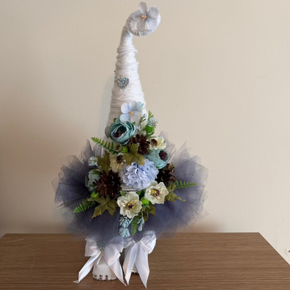 Decorative floral arrangement in a cone-shaped vase on a wooden surface with a beige background