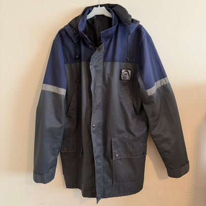 Two-tone blue and gray jacket with a brand logo on a beige background