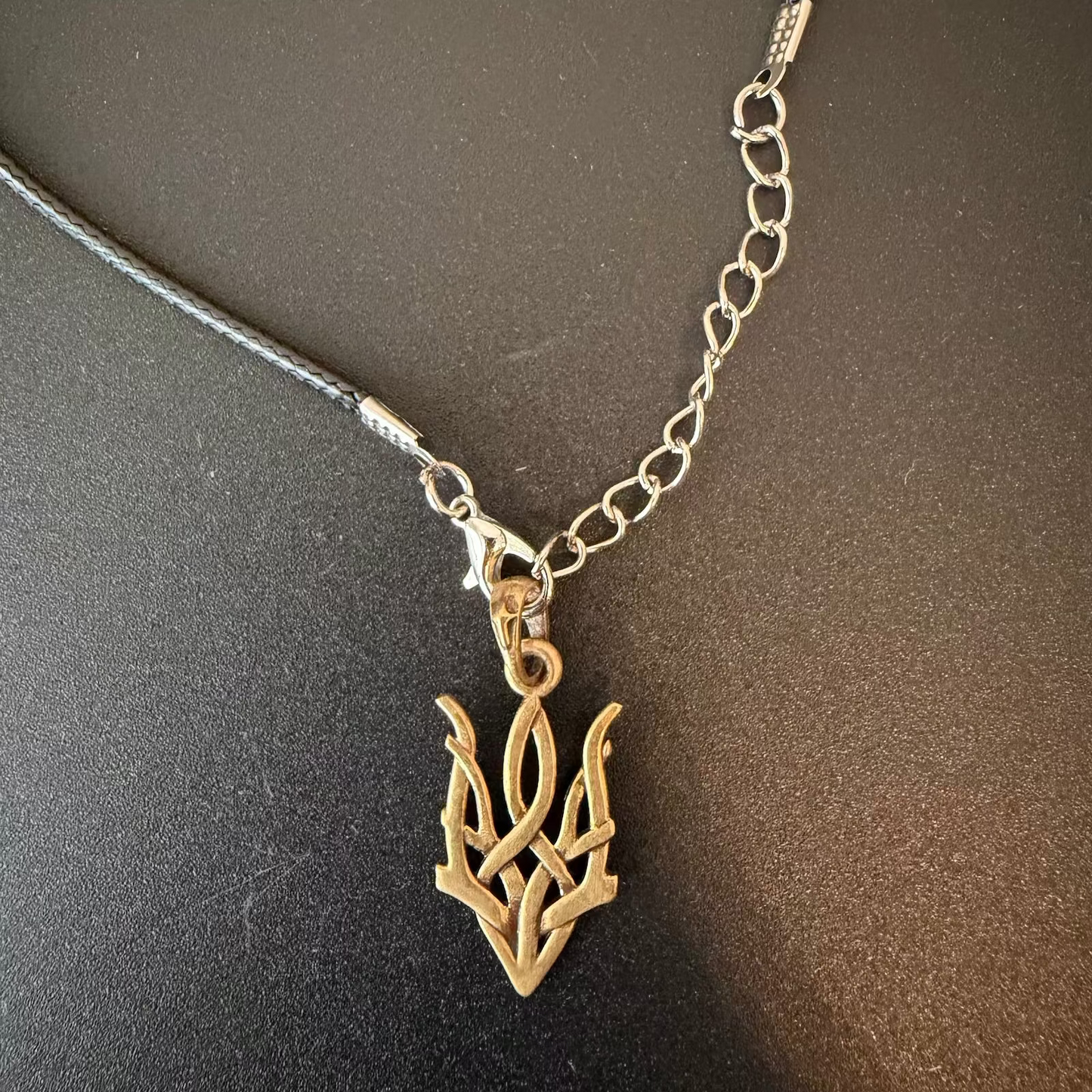 Necklace with a gold leaf-shaped pendant on a dark surface