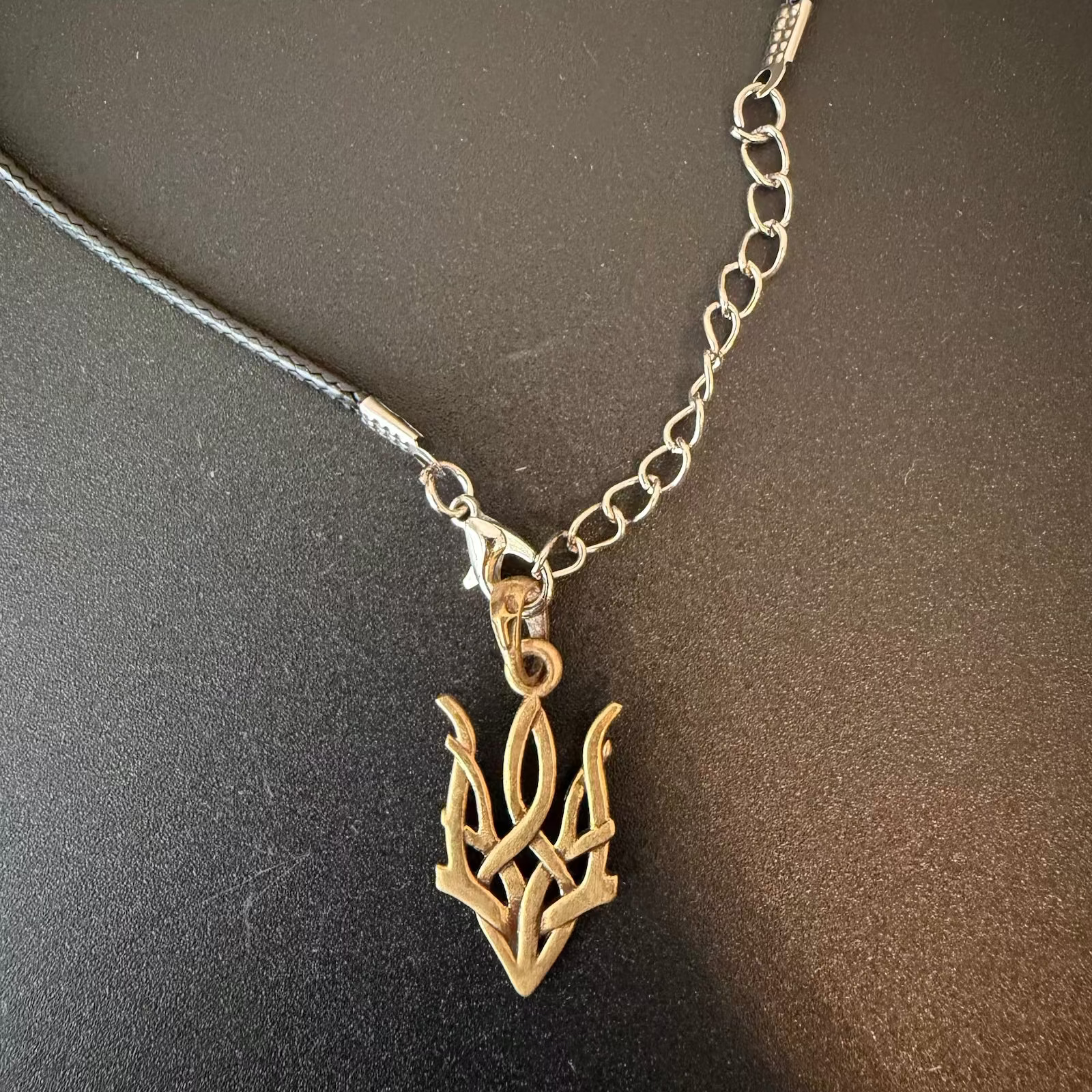 Necklace with a gold leaf-shaped pendant on a dark surface