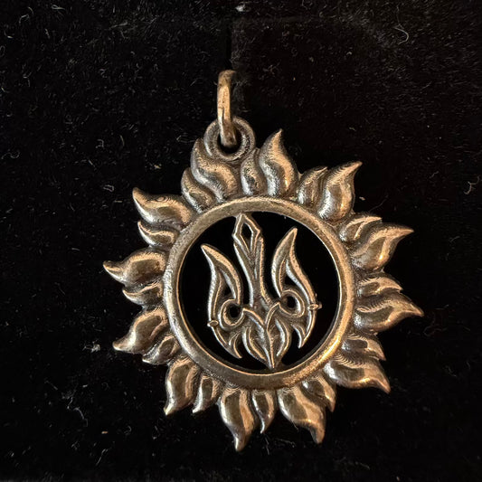 Silver pendant with a sun design on a black background