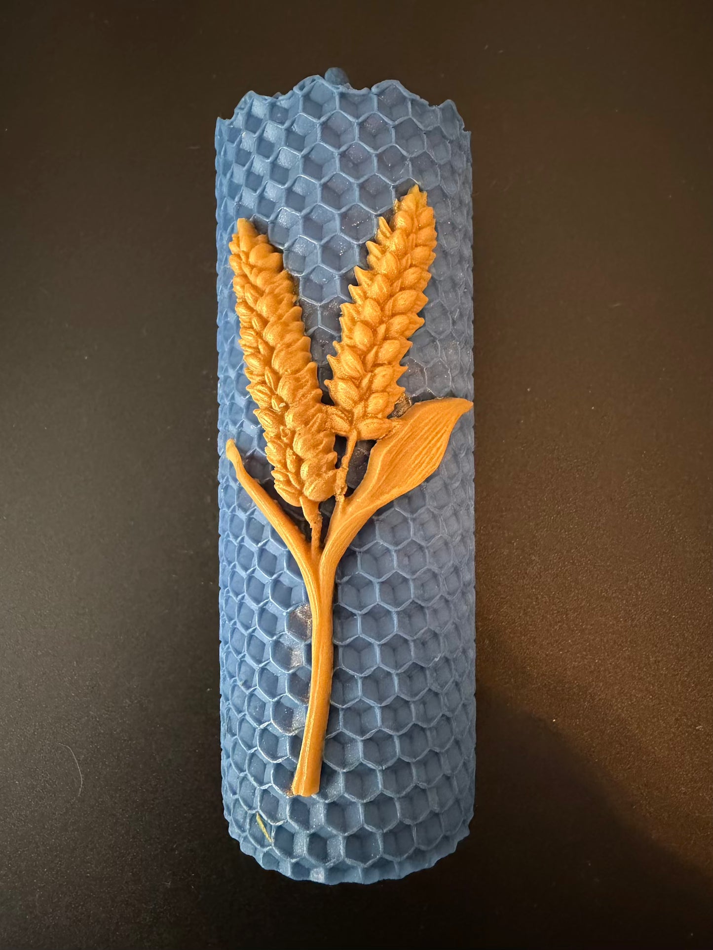 Blue honeycomb-shaped mold with gold wheat design on a dark background