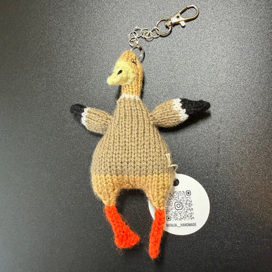 Knitted Goose keychain with a tag on a dark background