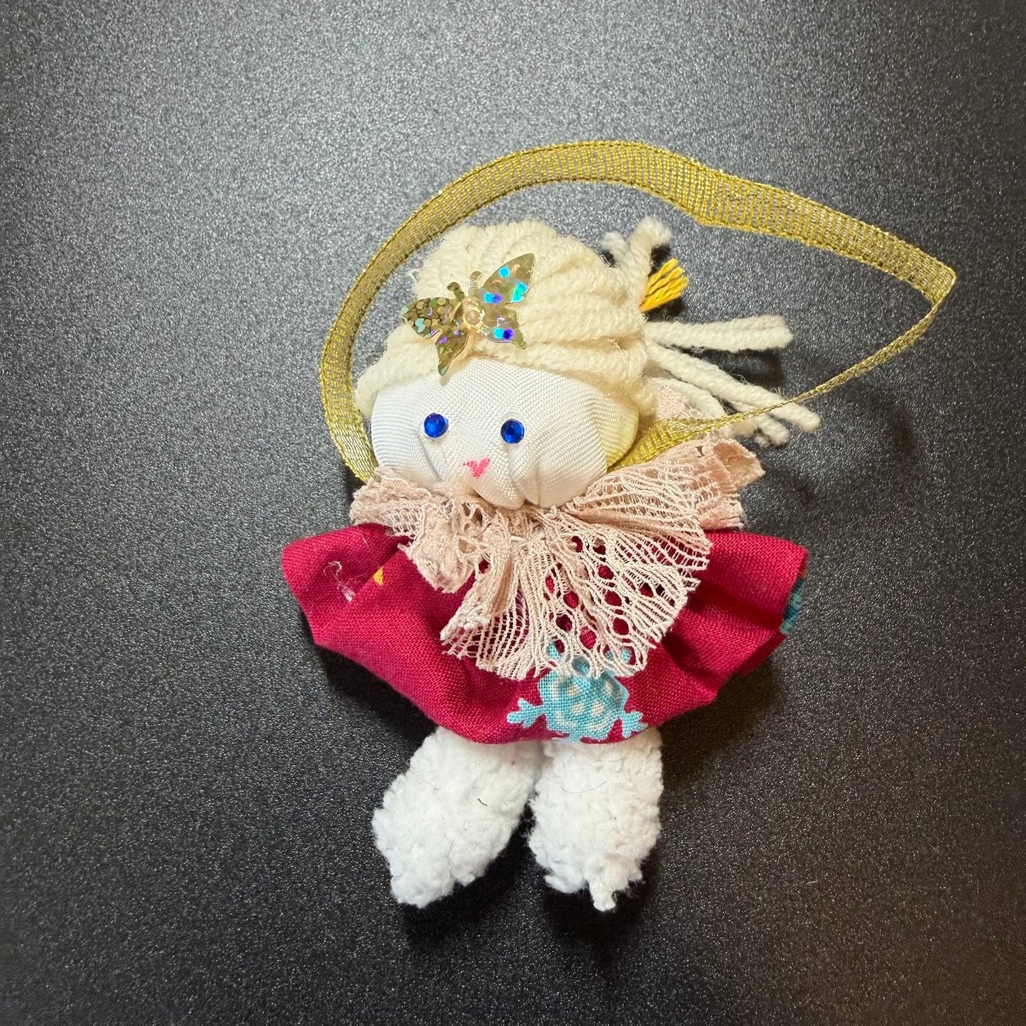 Small plush toy with decorative elements on a dark surface