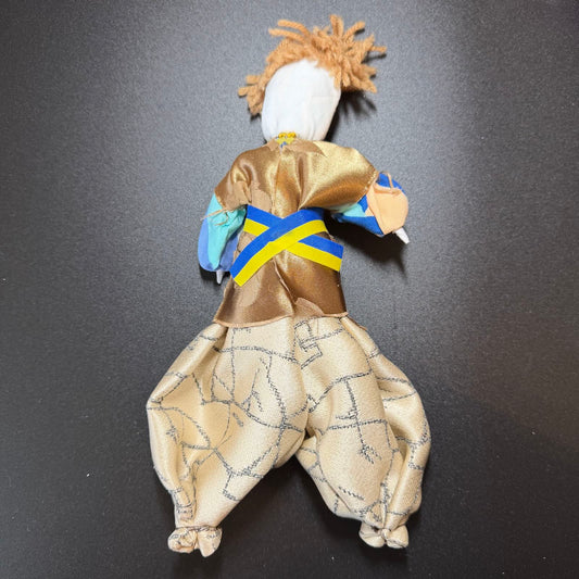 Textile figure with a gold outfit and blue sash on a black background