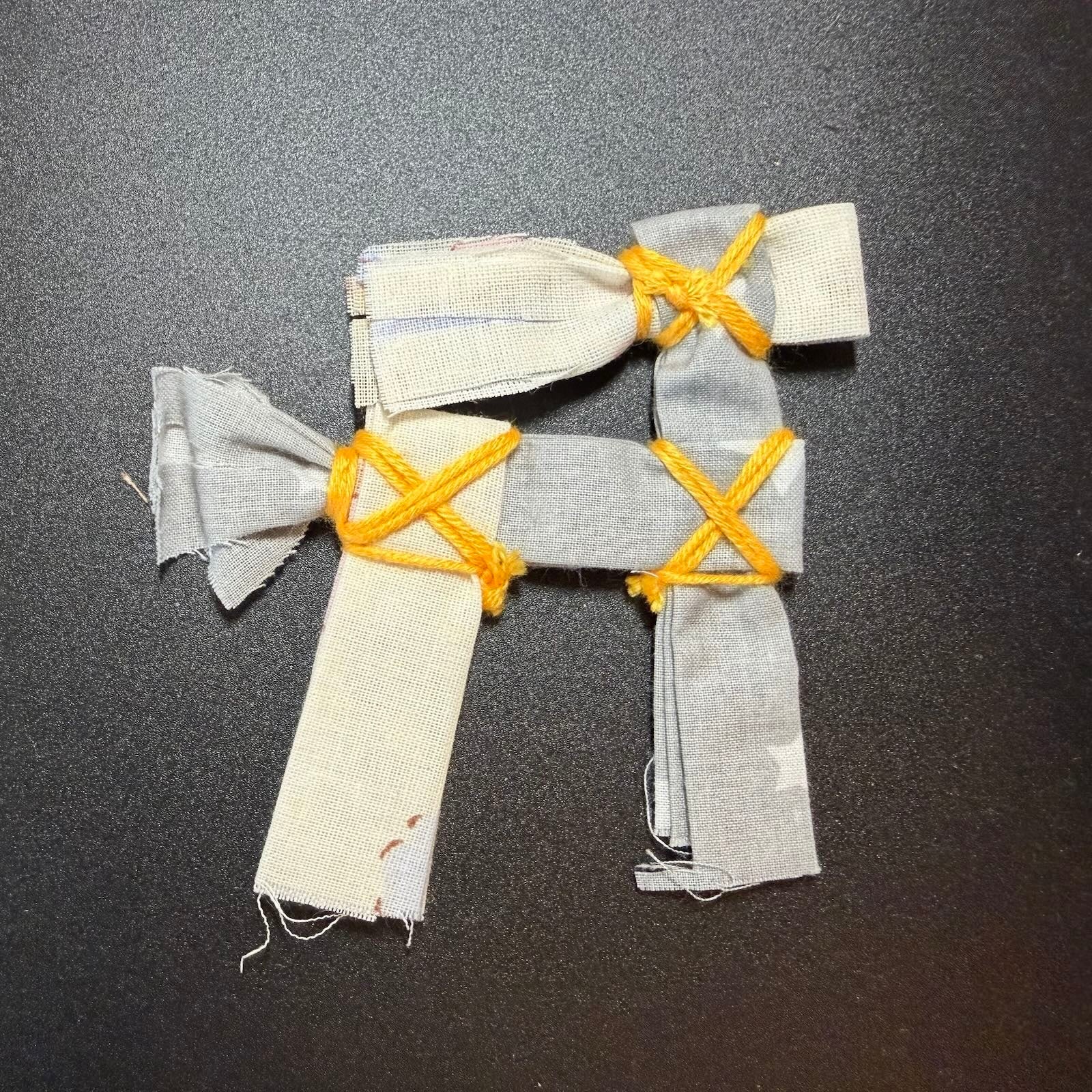 Fabric figure with yellow string on a dark surface