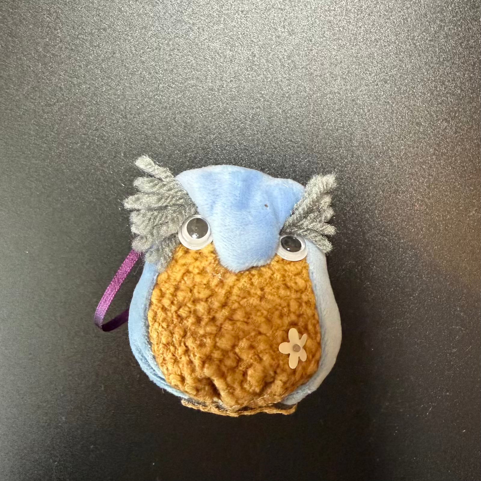Small crocheted owl toy on a metallic surface