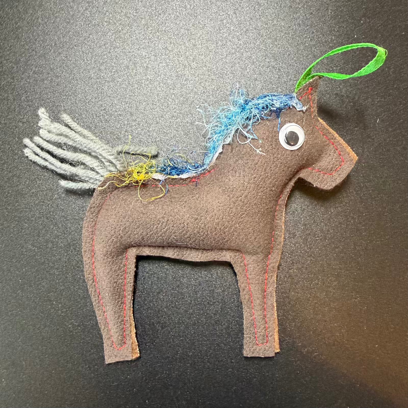 Brown horse-shaped toy with colorful mane on a gray background