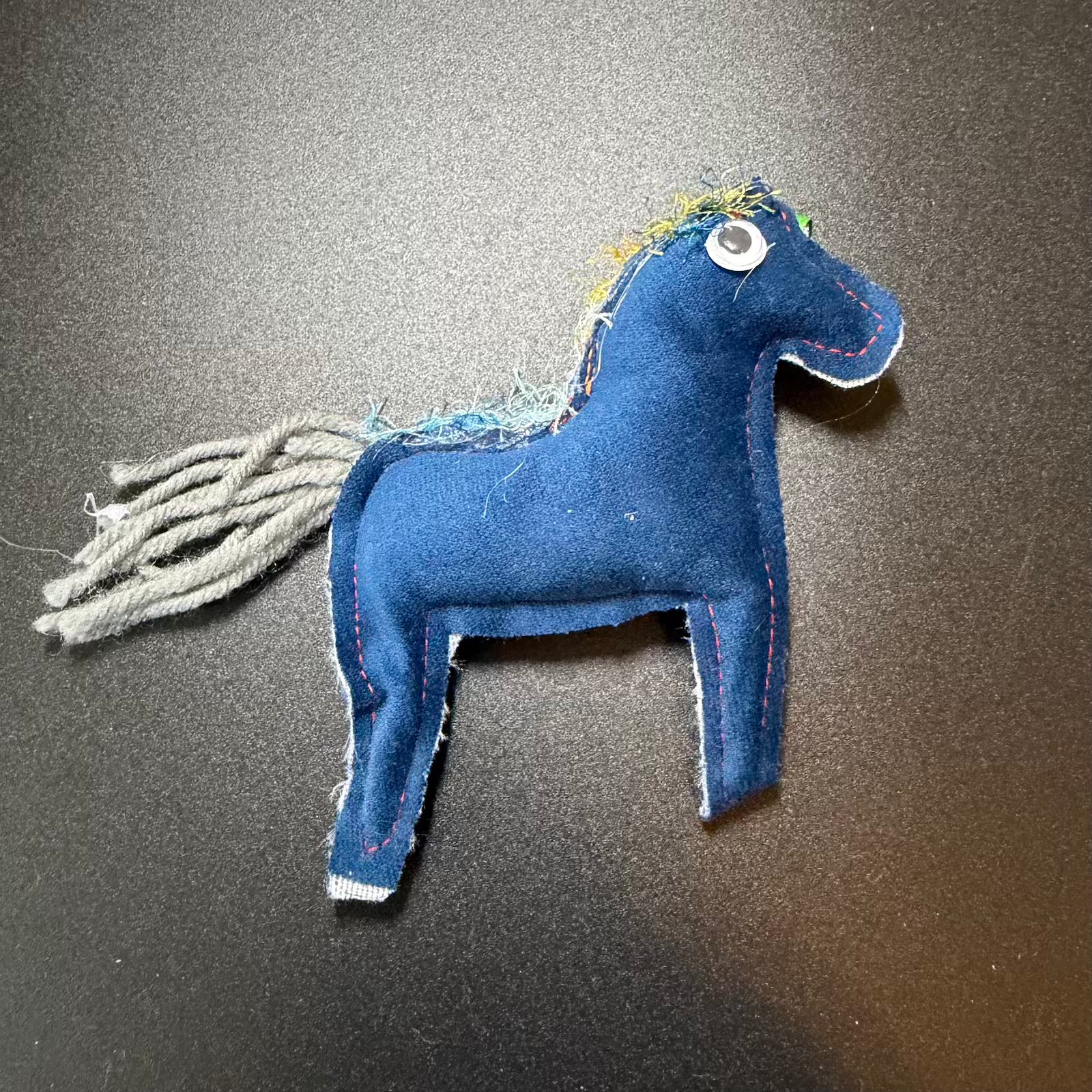 Blue fabric horse toy on a dark surface