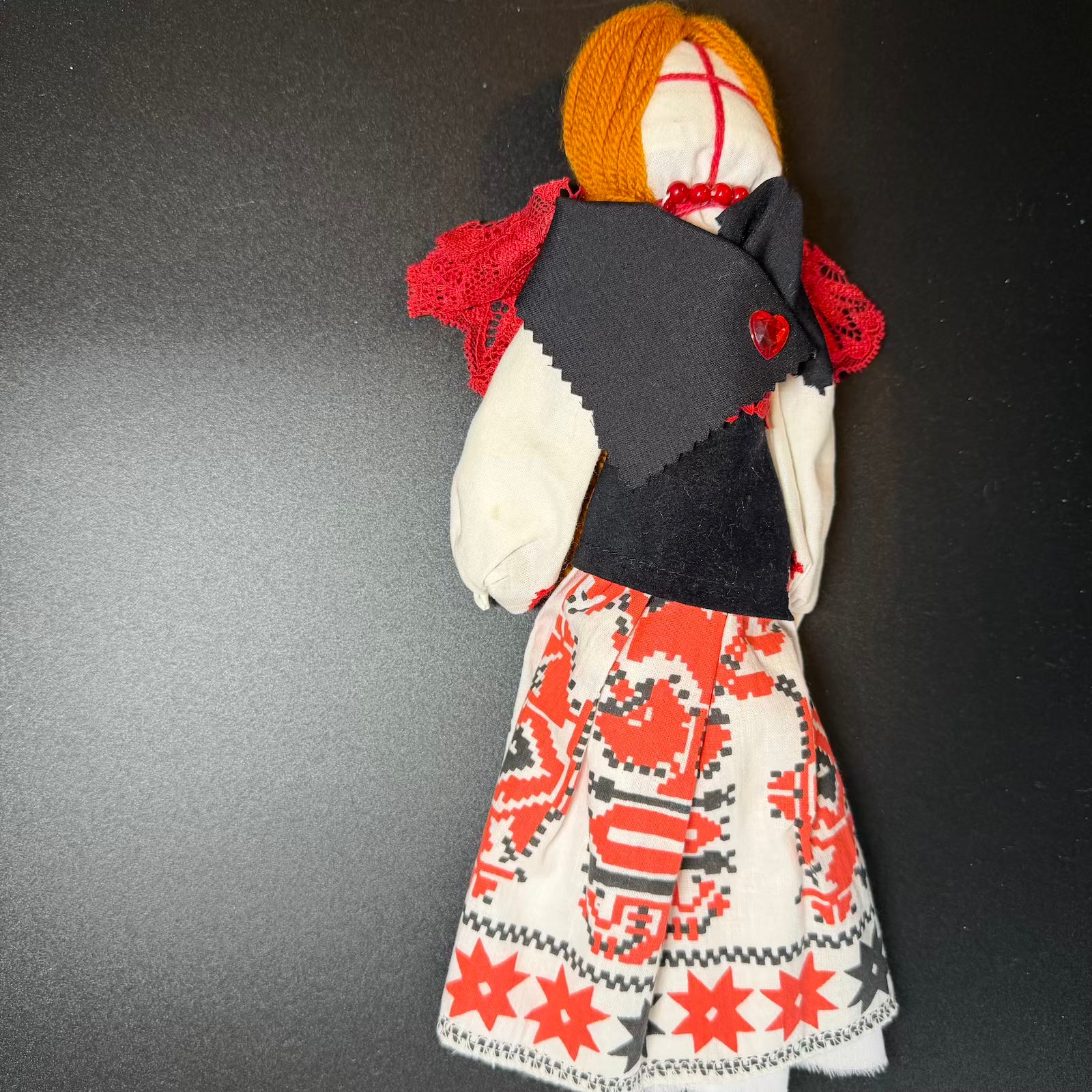 Handmade doll with a patterned dress on a dark background