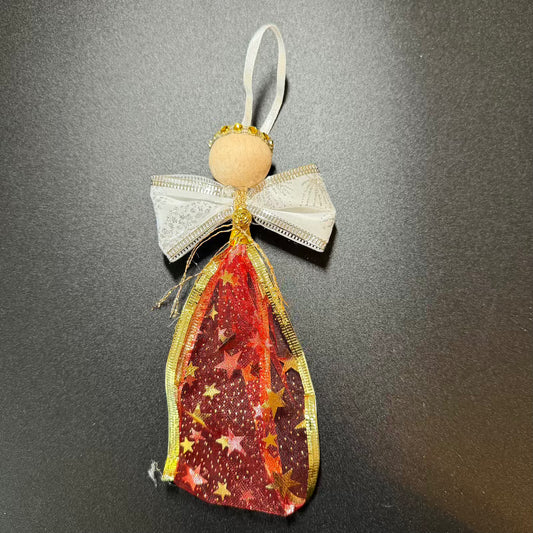 Decorative angel ornament with red and gold star pattern on a dark background