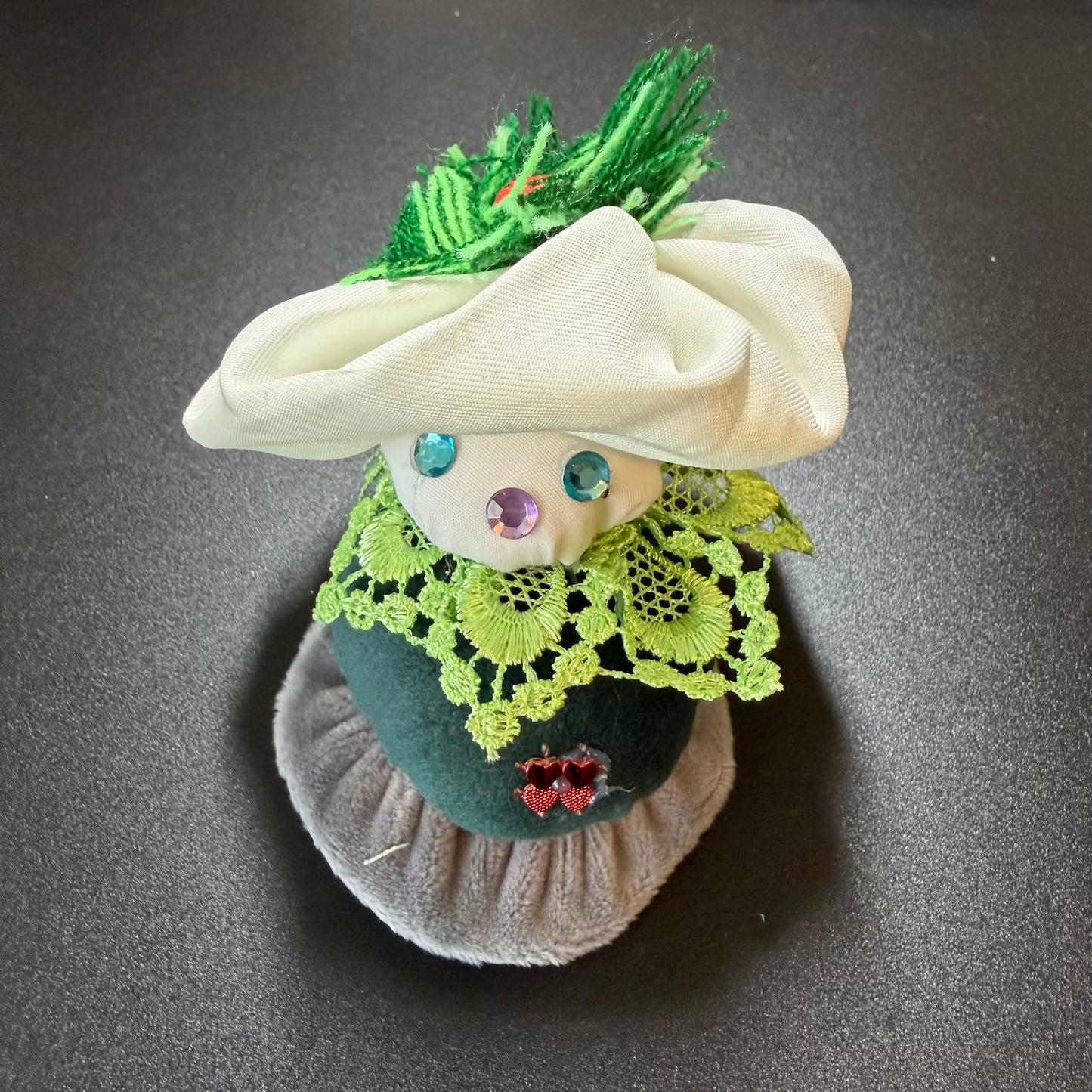 Decorative head with green hat, lace details, and colorful eyes on a dark background