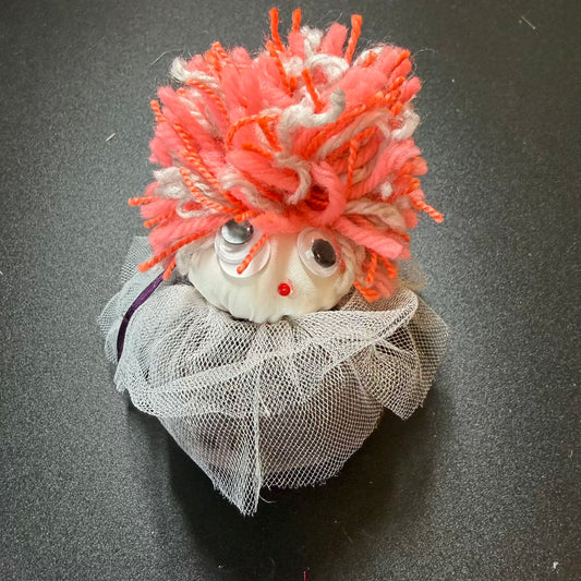 Small creature with orange hair and a white outfit on a dark background