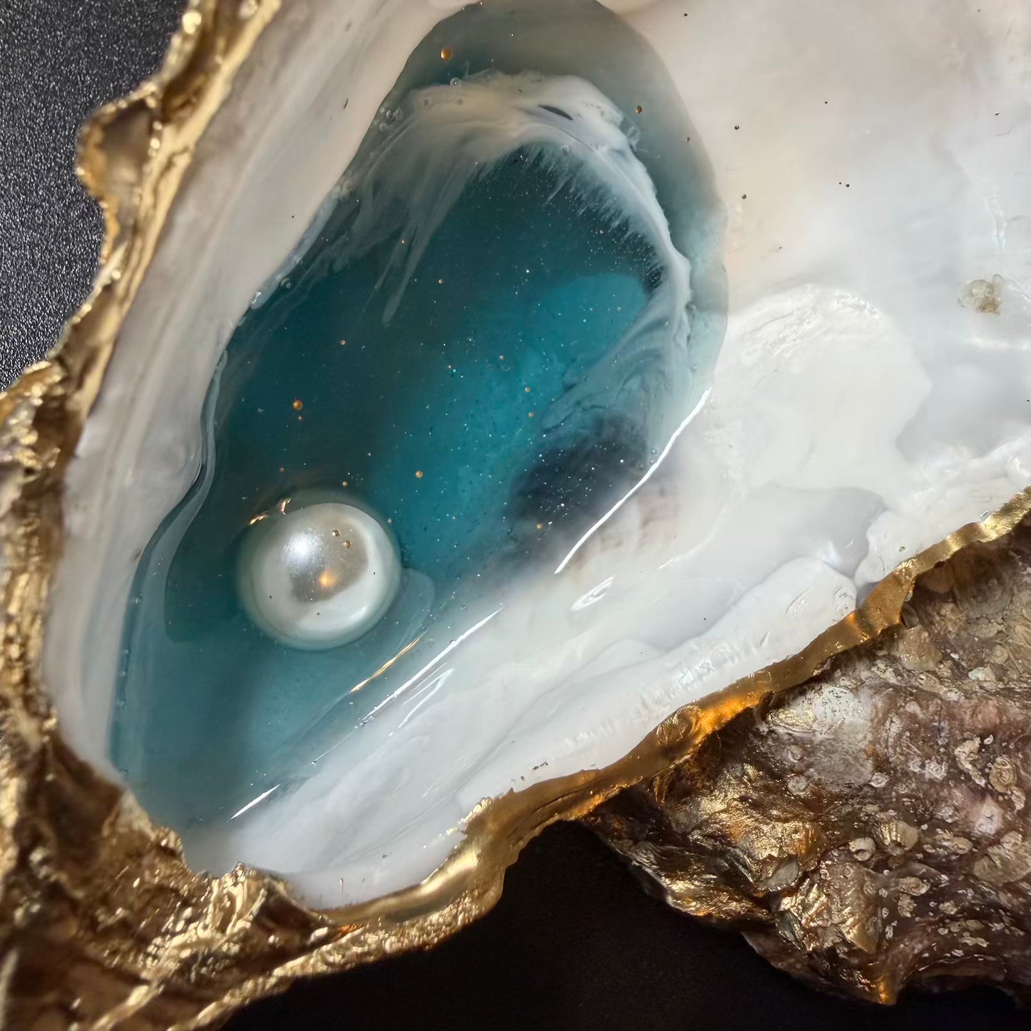 Pearl inside a cracked shell with blue interior and gold rim
