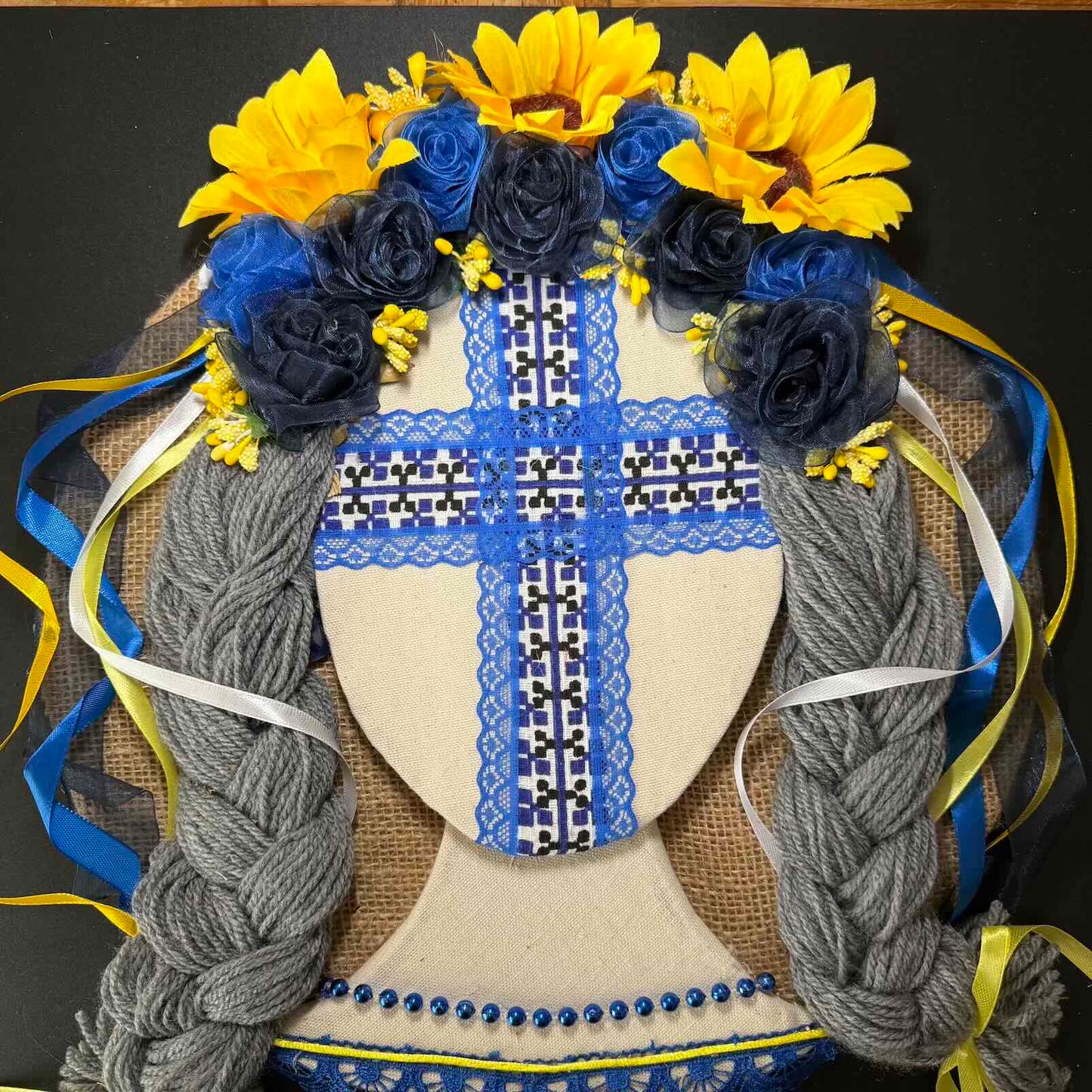 Decorative headband with blue and yellow flowers and braided hair on a black background