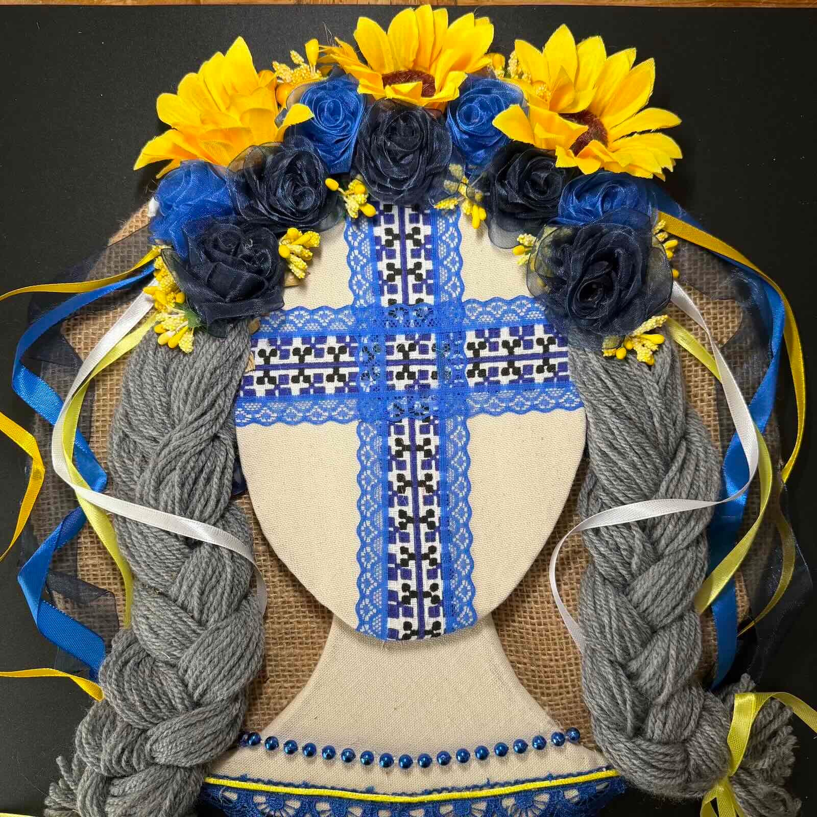 Decorative headband with blue and yellow flowers and braided hair on a black background