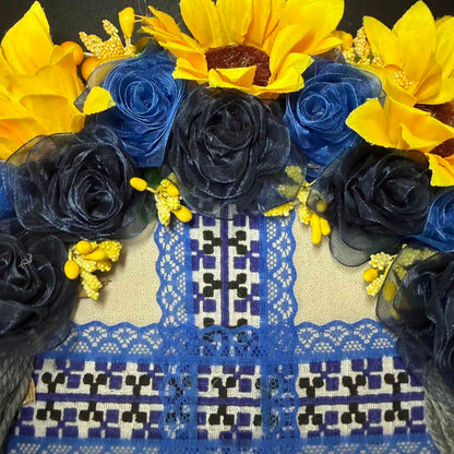 Decorative arrangement of yellow sunflowers and blue roses on a patterned fabric background