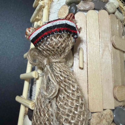 Close-up of a handmade structure made from popsicle sticks and rope with a dark background.