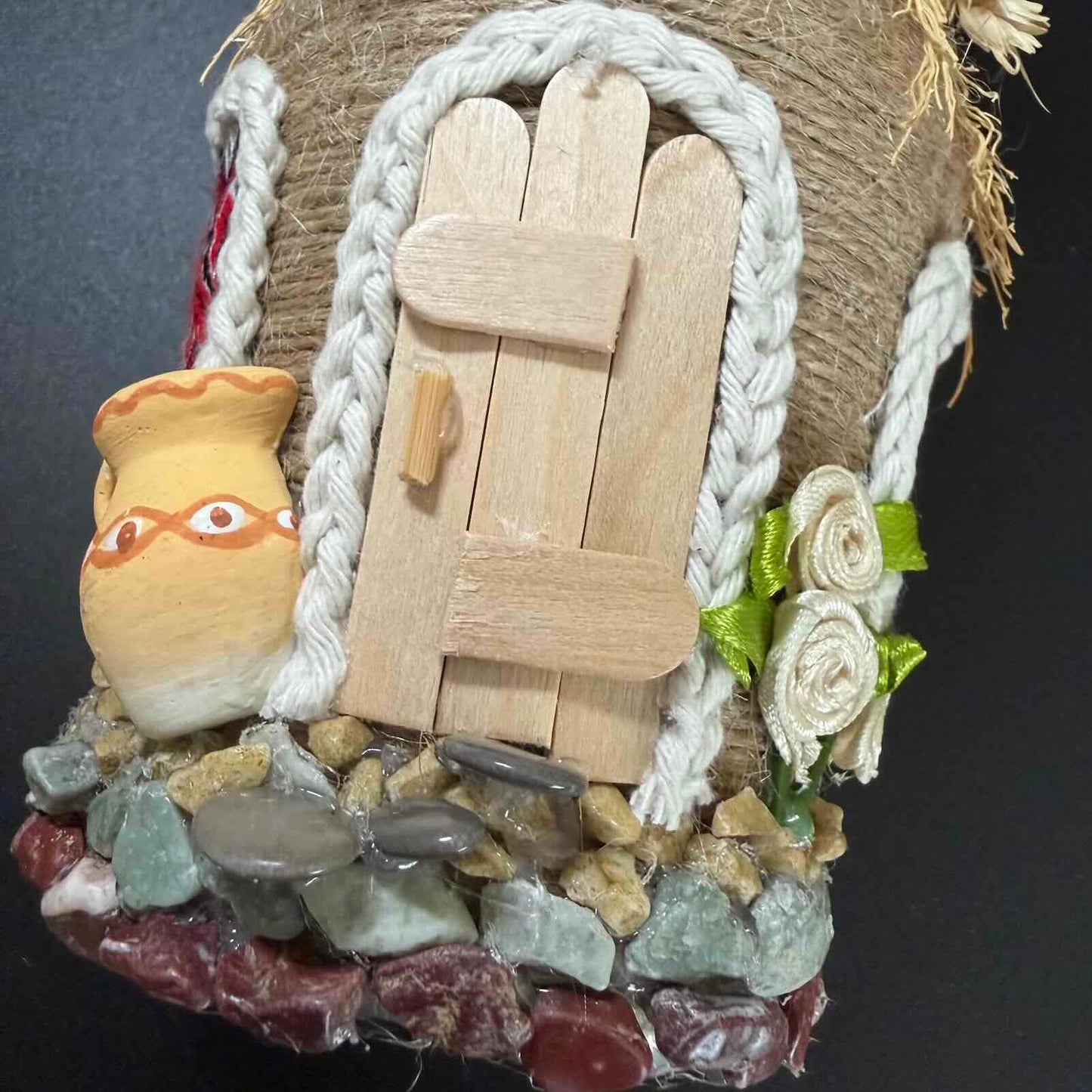 Decorative fairy door with a small pot, flowers, and stones on a dark background
