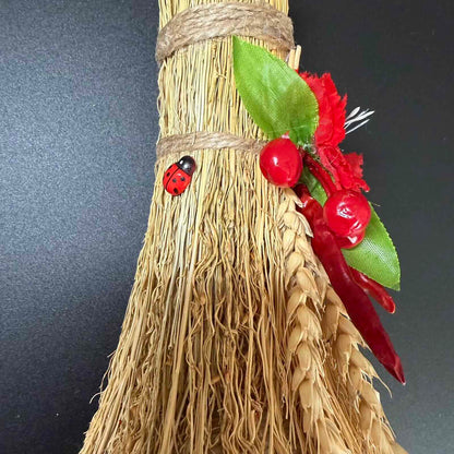 Decorative broom with red berries and ladybugs on a dark background
