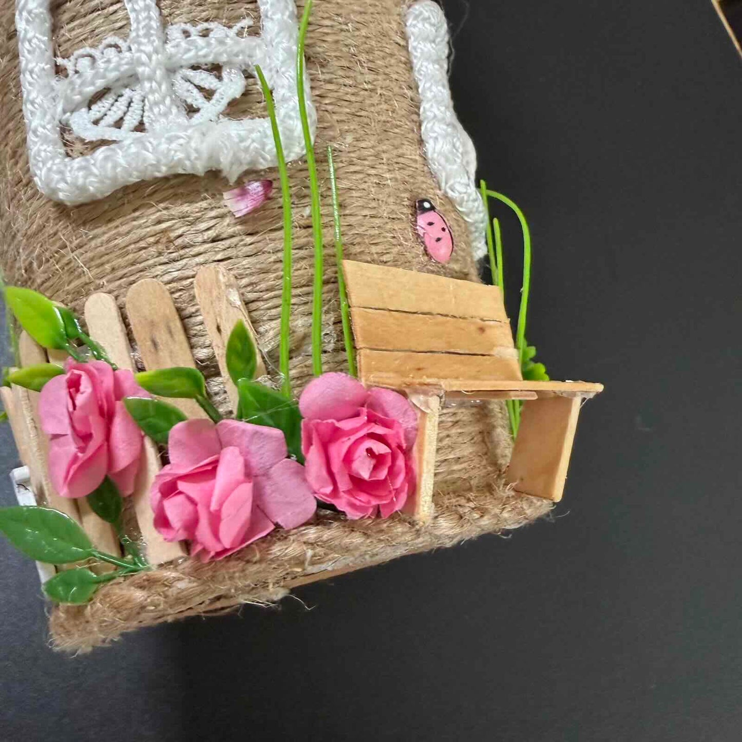 Small wooden bench with pink flowers and greenery on a textured surface