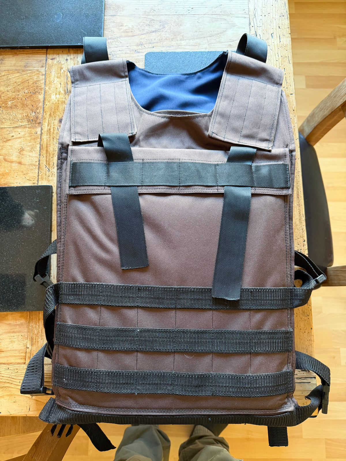 Front view of the handmade brown Ukrainian body-armour carrier, with black webbing, shoulder fastenings and adjustable waist straps.
