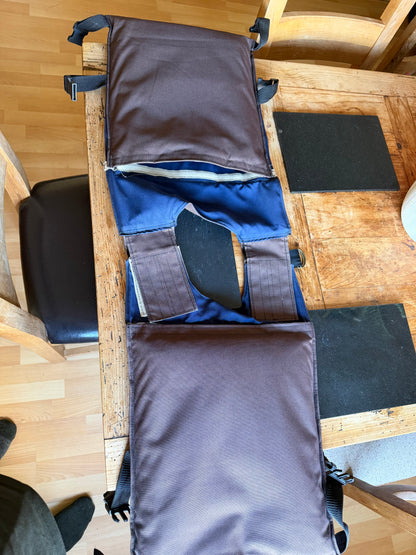 Opened handmade Ukrainian body-armour carrier showing its brown outer fabric, blue internal plate sleeves and adjustable fastening straps.