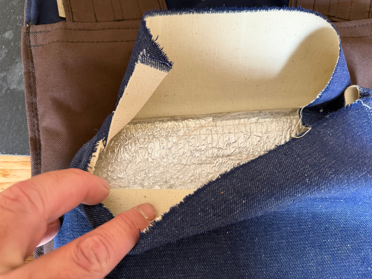 Open blue fabric plate sleeve inside the improvised Ukrainian body armour, revealing the edge of a steel plate beneath its protective wrapping.