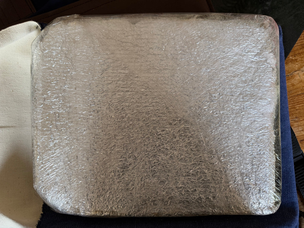 Close-up of the second heavy steel armour plate, showing its rounded corners, protective material and layers of clear plastic wrapping.