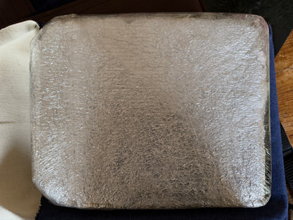 Close-up of the second heavy steel armour plate, showing its rounded corners, protective material and layers of clear plastic wrapping.