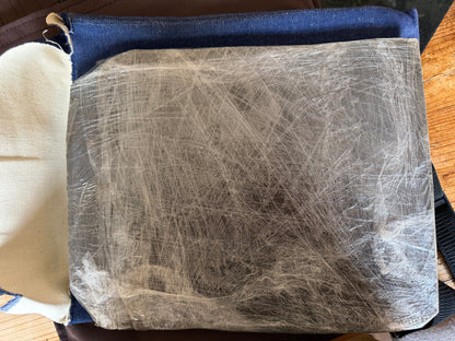 Close-up of one handmade steel armour plate covered with fibrous anti-spall material and tightly wrapped in clear plastic film.