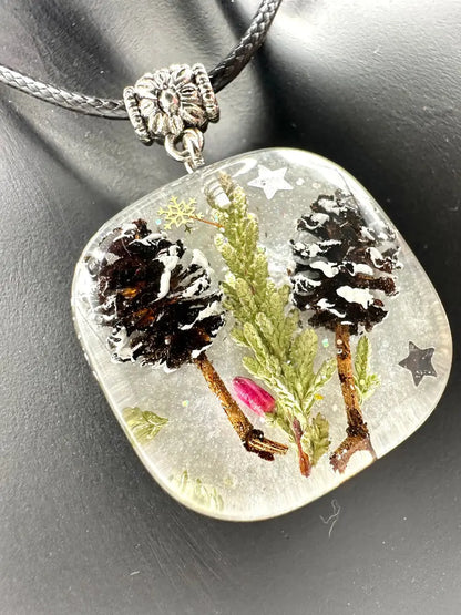 Necklace with a pendant featuring nature-themed design on a dark background
