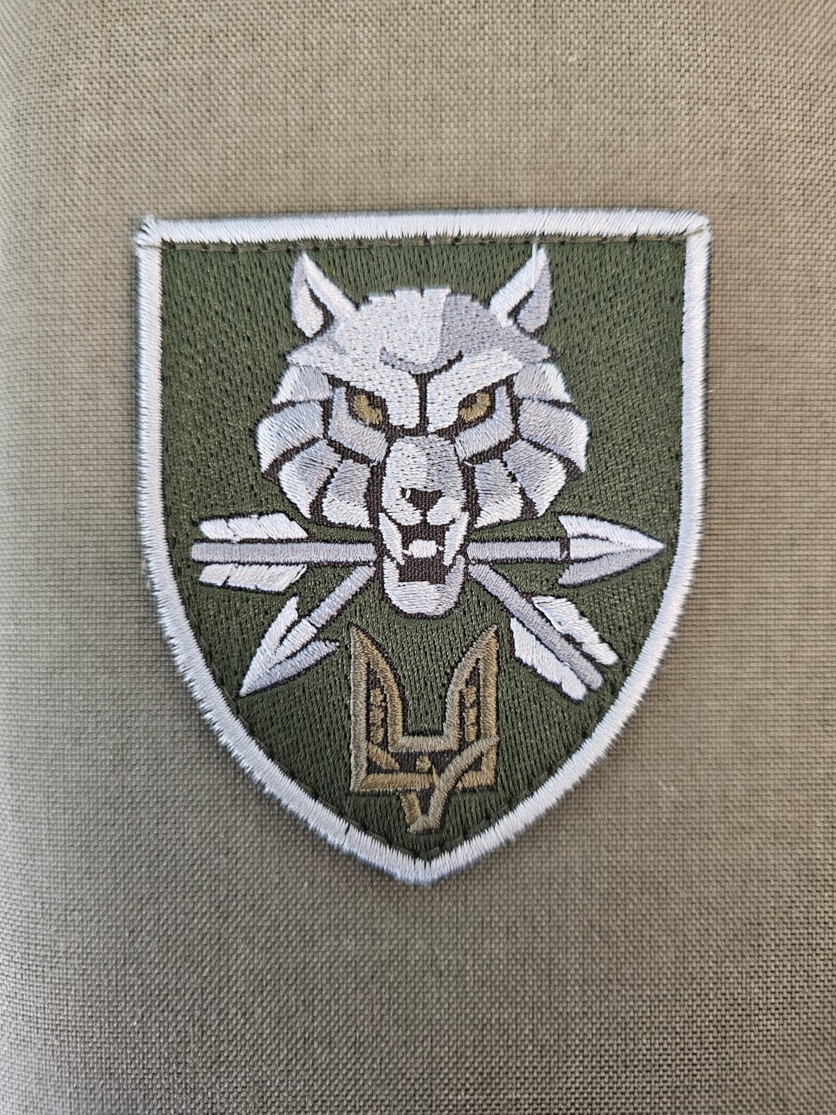 A Fabric patch featuring a Wolf holding two arrows in its mouth