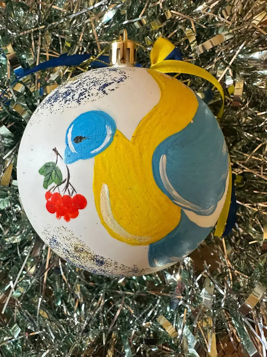Hand painted Christmas bauble with a bird and cherries design, from Ukraine, with a blue and yellow color scheme.