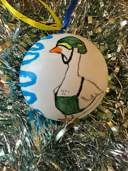 Hand painted Christmas bauble with a depiction of a duck, set against a blue and green background, with a silver and blue glittery finish.