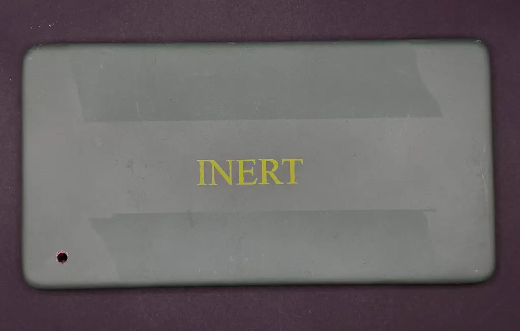 Rectangular gray object with 'INERT' text on a purple background
