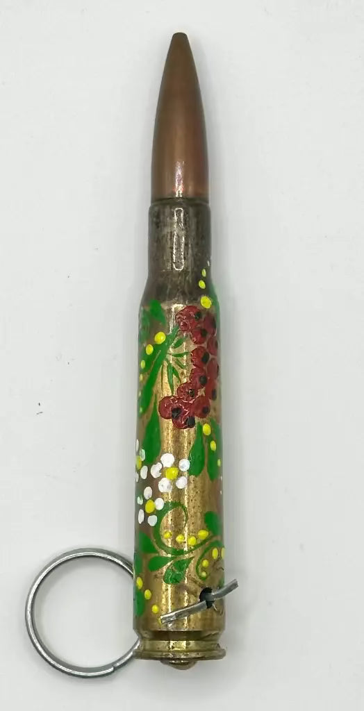 Decorative keychain made from a bullet casing with floral designs on a white background