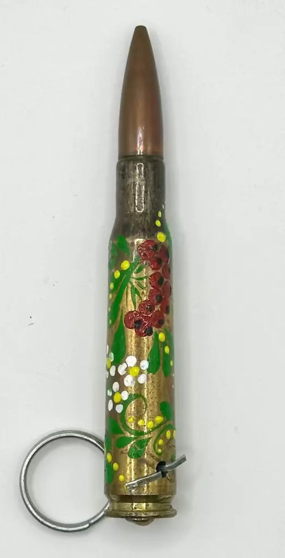 Decorative keychain made from a bullet casing with floral designs on a white background