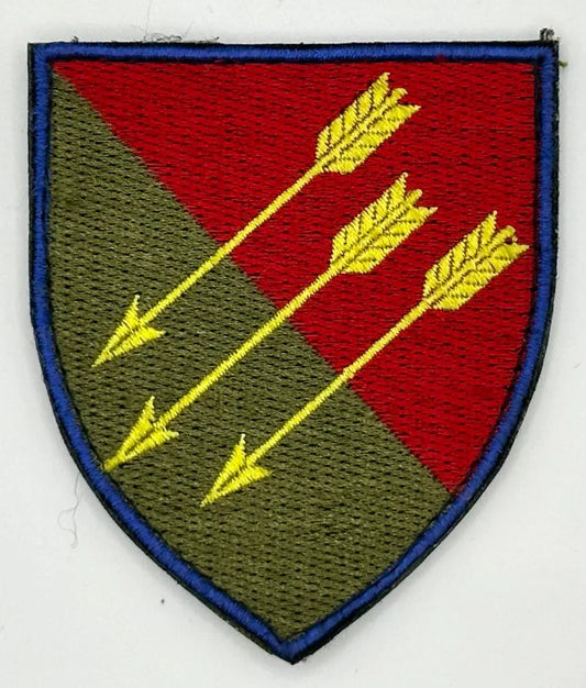 Embroidered patch with red and green shield design and yellow arrows on a white background