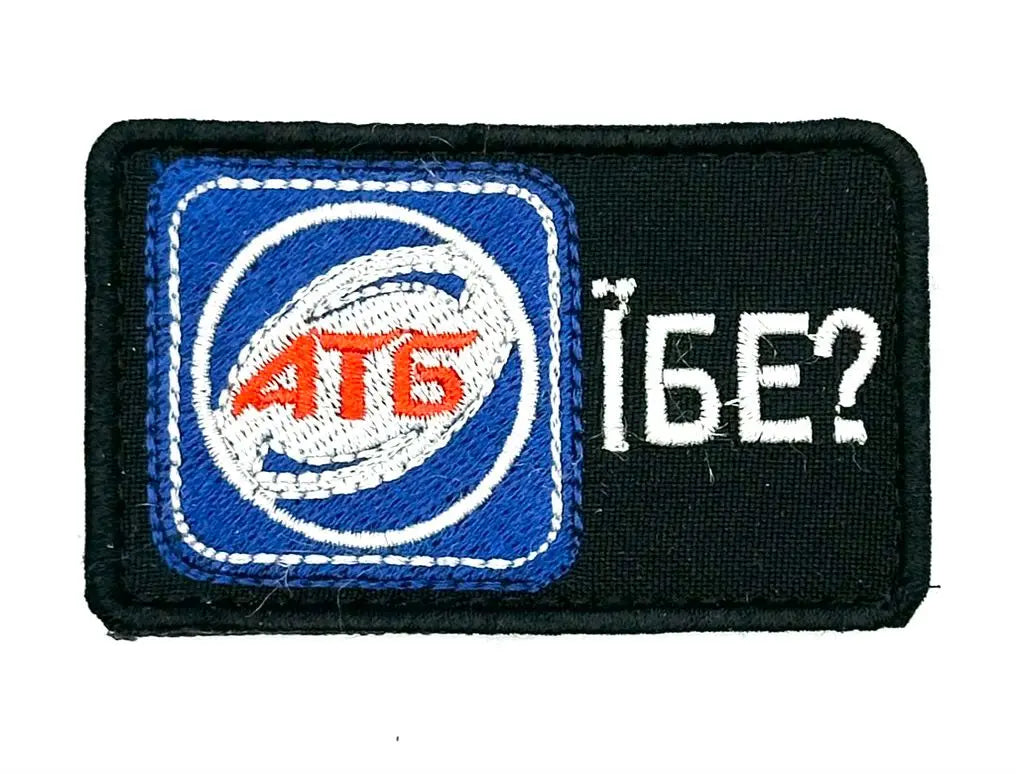 A morale patch with a blue and white design featuring text and a symbol, on a black background.