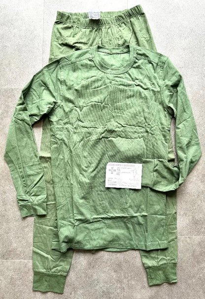 Green long-sleeve shirt and pants laid flat on a gray surface